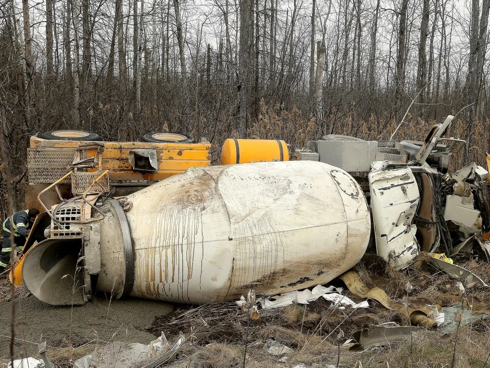 Wrecked cement mixer truck being lifted after a highway crash
